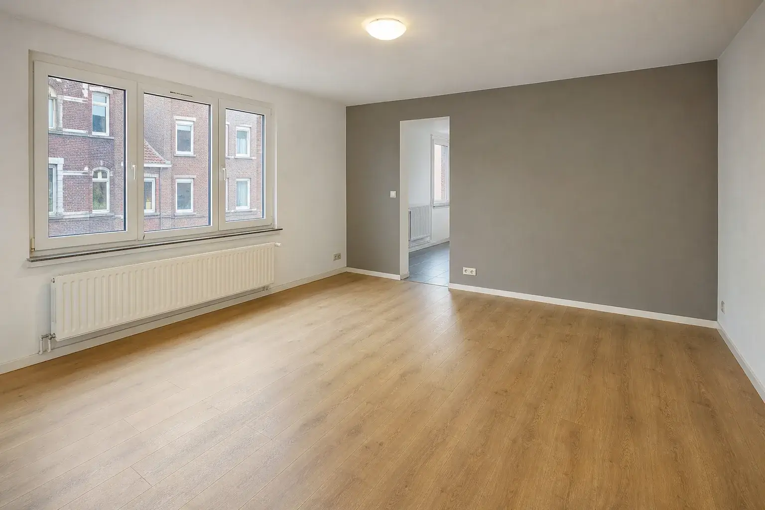 Empty living room with wooden floor and grey wall, as listed